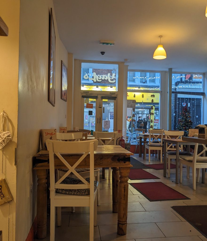 Photo of the inside of Yaylo cafe, showing tables and chairs and windows overlooking the street.